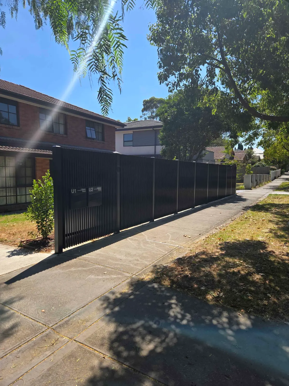 Black blade steel front fence running along a footpath in front of a townhouse