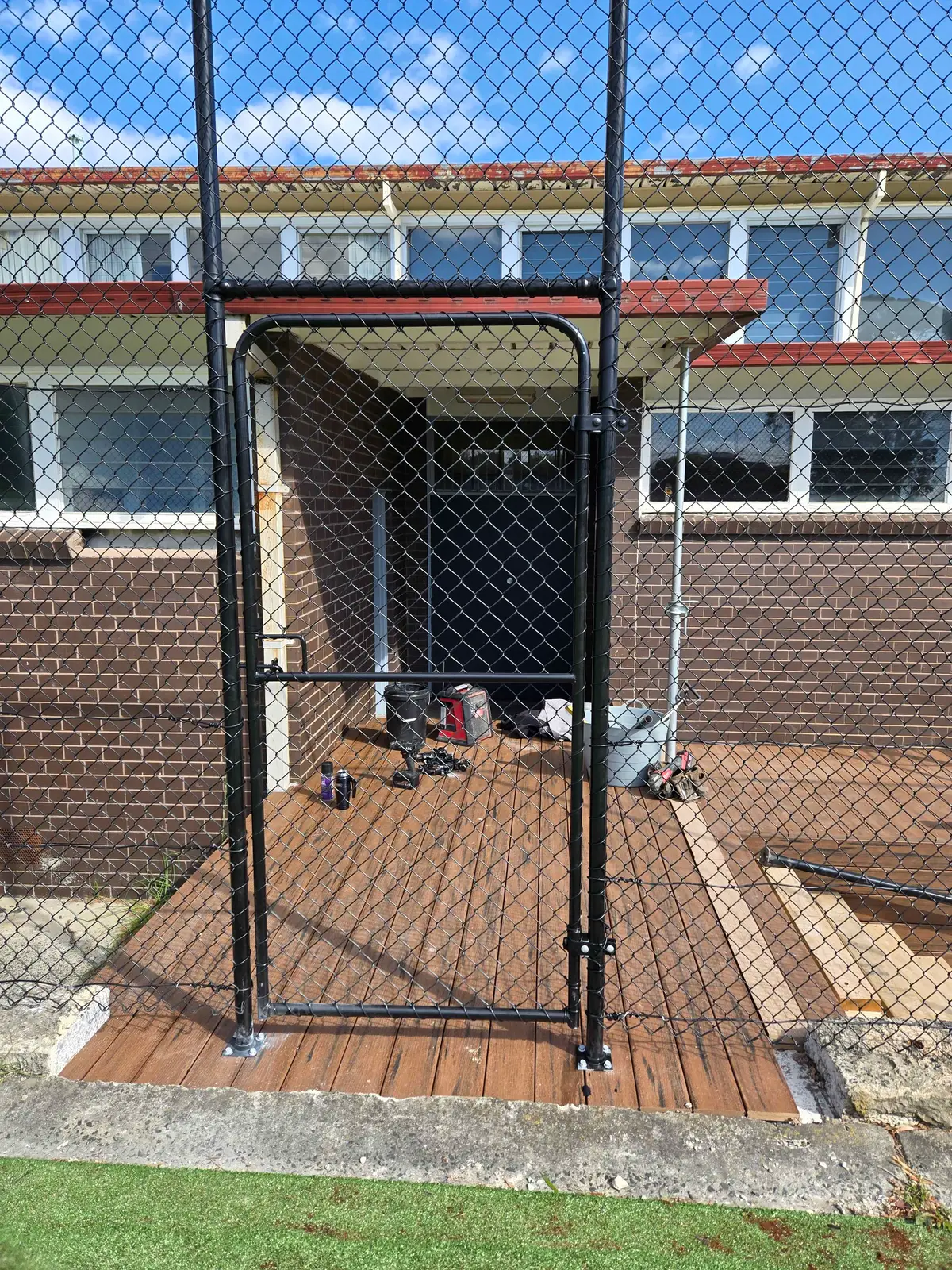 Black chain mesh gate in front of a school building on a decked walkway