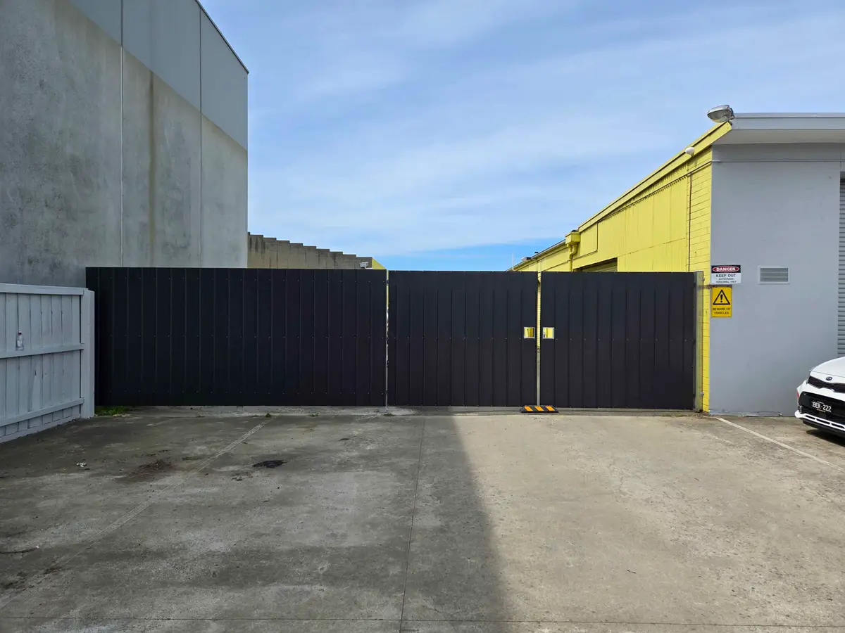 Black Colorbond double gates closing off a factory driveway