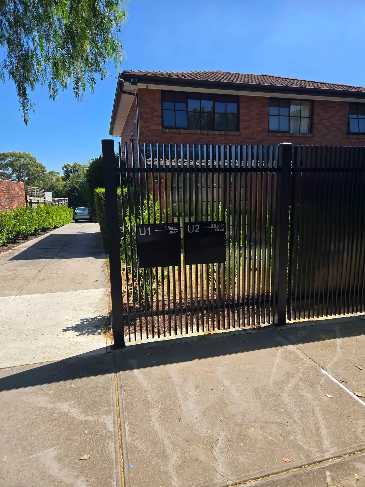 Close view of a black vertical blade steel front fence with two unit letterboxes