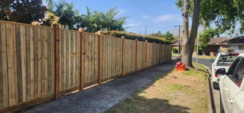 Capped paling fence with a matching gate along a footpath