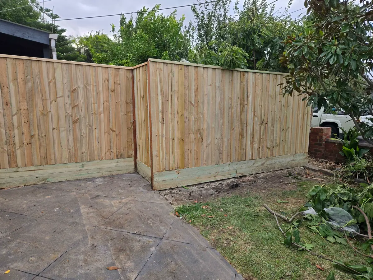 Capped paling fence turning a corner with a plinth on a paved area