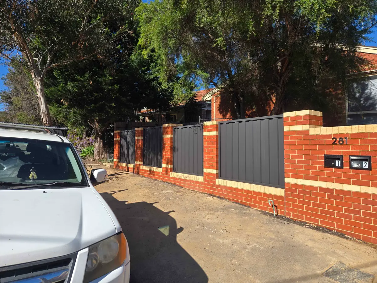 Brick and Colorbond front fence with two built-in letterboxes and the street number at a unit driveway
