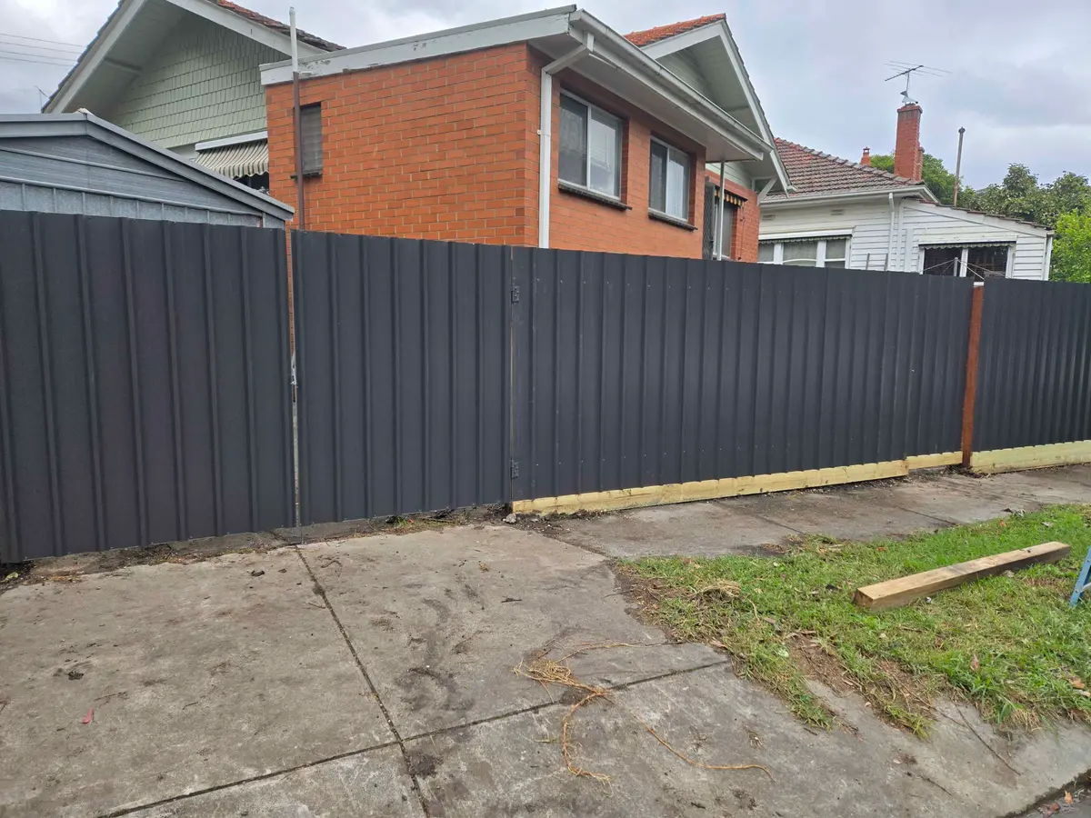Monument Colorbond fence with a matching gate beside a brick house