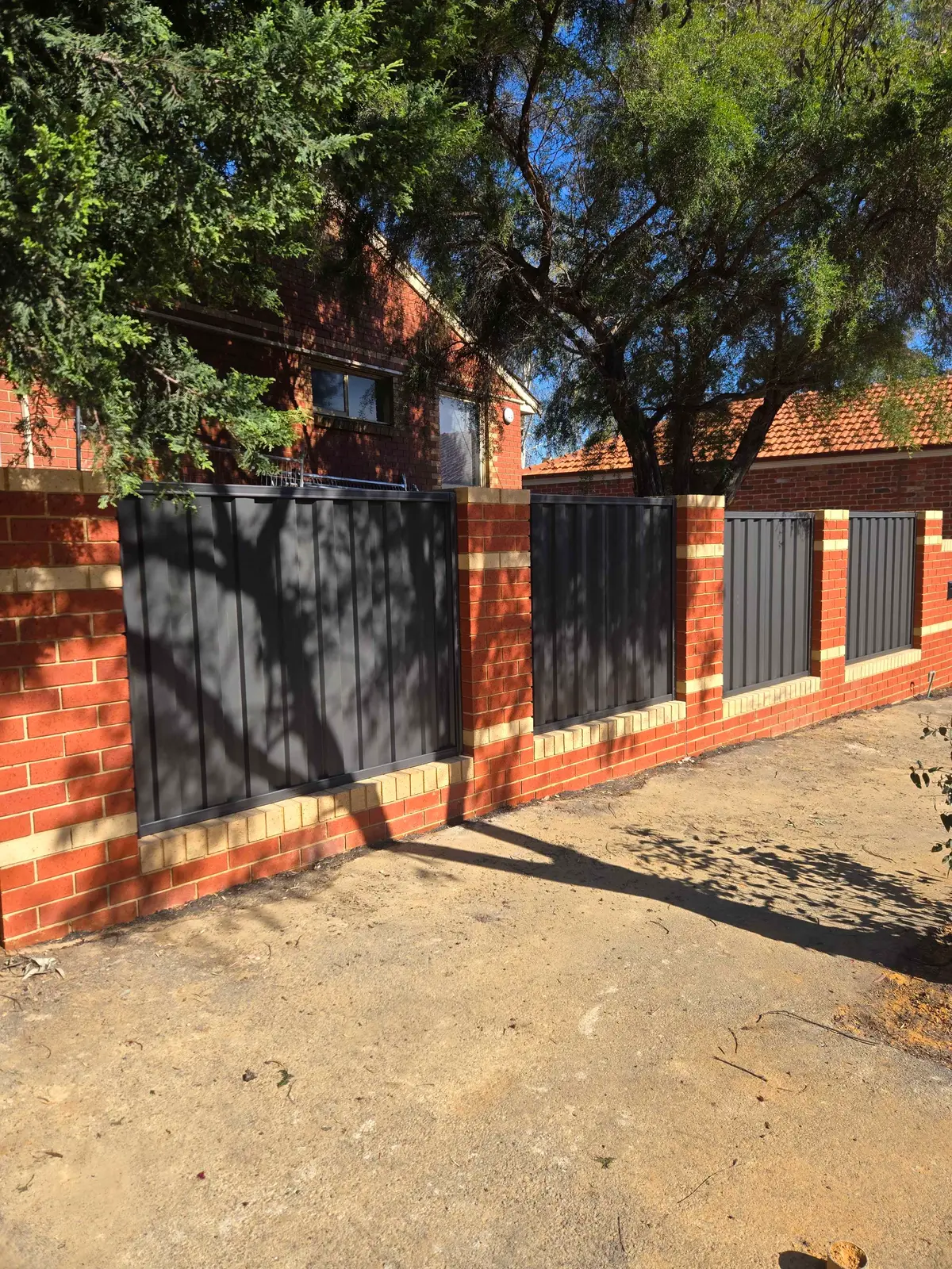 Close view of a Colorbond infill panel framed by red brick piers with a blonde brick plinth below