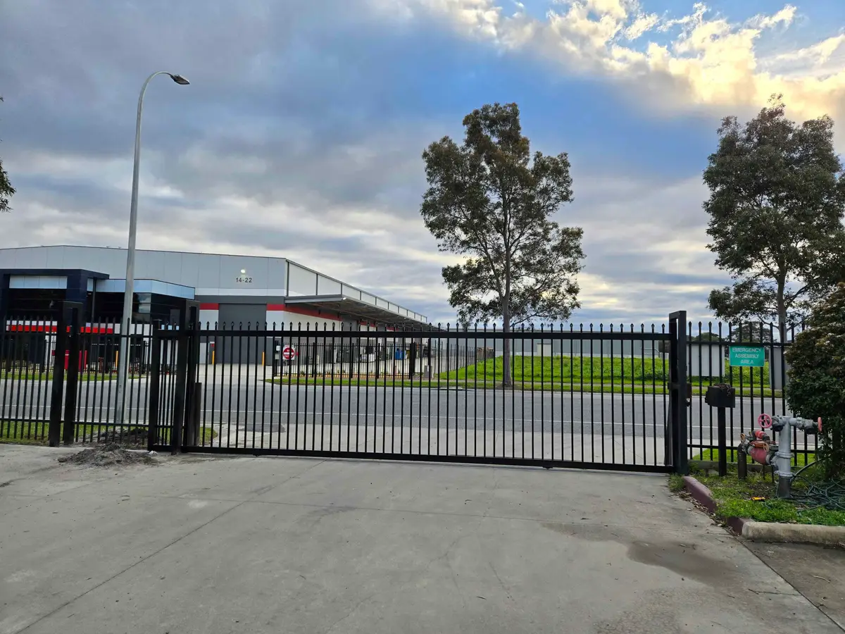 Black spear-top steel sliding gate at a warehouse entrance