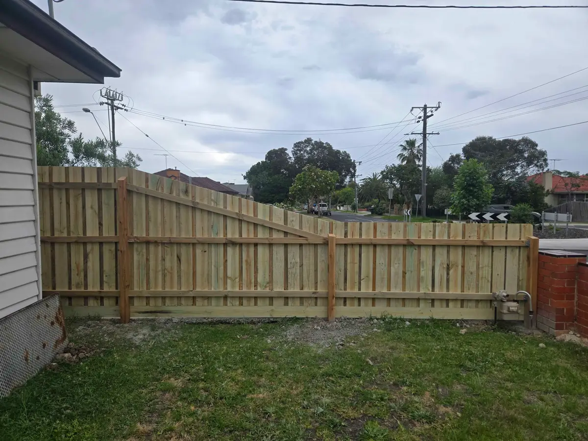 Side view of a paling fence raked down along a driveway on a corner block