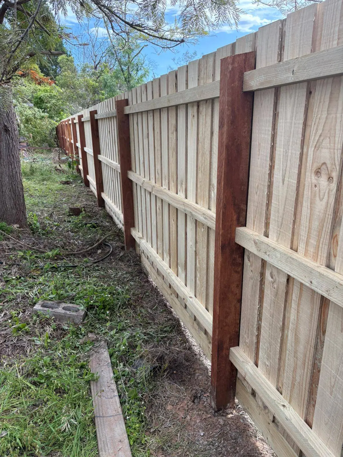 Close view of the rear of a paling fence showing a hardwood post and three rails