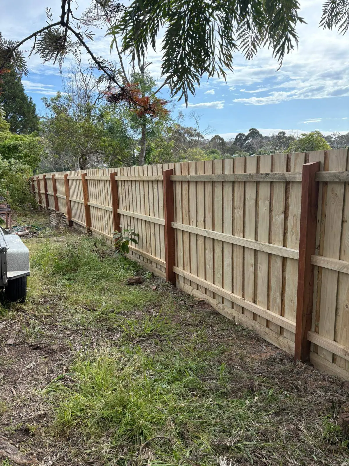 Rear view along a long paling fence with hardwood posts and rails