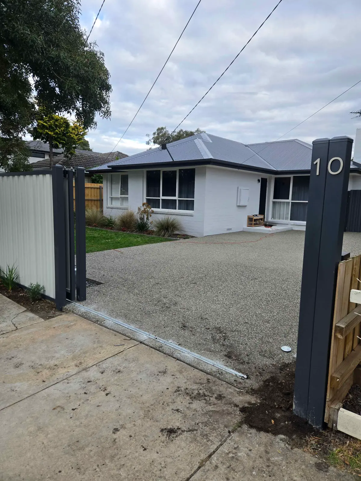 Sliding driveway gate with dark steel posts and a Colorbond fence panel