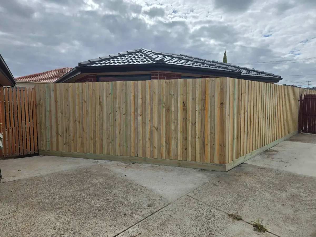 New treated pine paling fence on a plinth wrapping the corner of a driveway