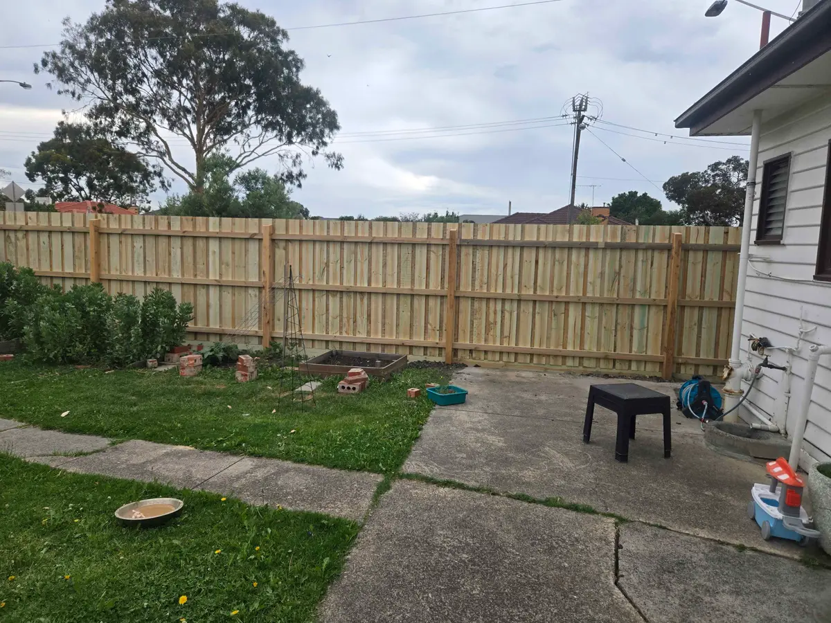 Backyard paling fence with hardwood posts and three rails beside a vegetable garden